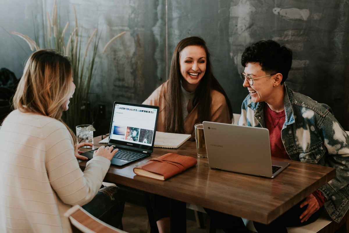 3 étudiants qui travaillent et rient ensemble à une table