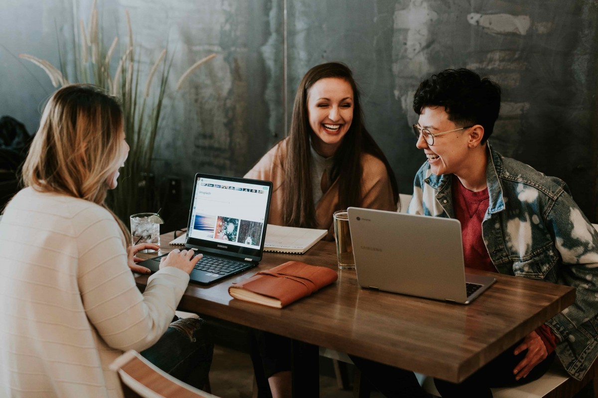 3 étudiants qui travaillent et rient ensemble à une table