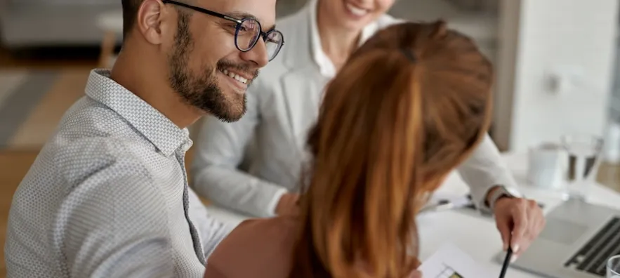 jeune couple heureux et leur agent immobilier ayant une réunion au bureau