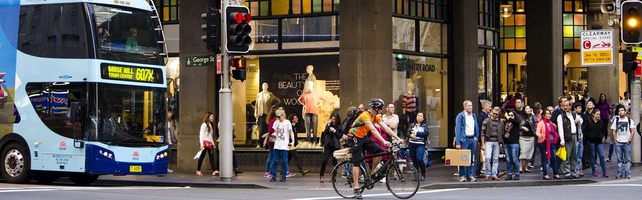  intersection où l’on voit un bus, un cycliste et des piétons qui se partagent la voie publique.