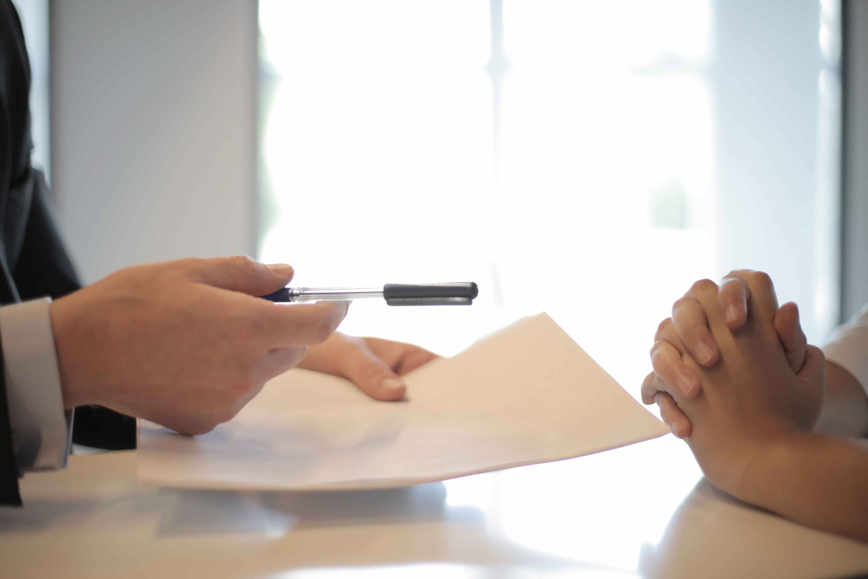 Un banquier propose à un acheteur dans l’immobilier neuf de signer son offre de prêt immobilier.