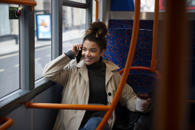 Jeune femme au téléphone, installée à l’intérieur d’un bus express