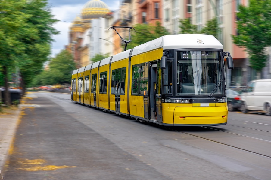 Tramway jaune circulant dans une rue urbaine bordée d’arbres entre Lyon et Vénissieux